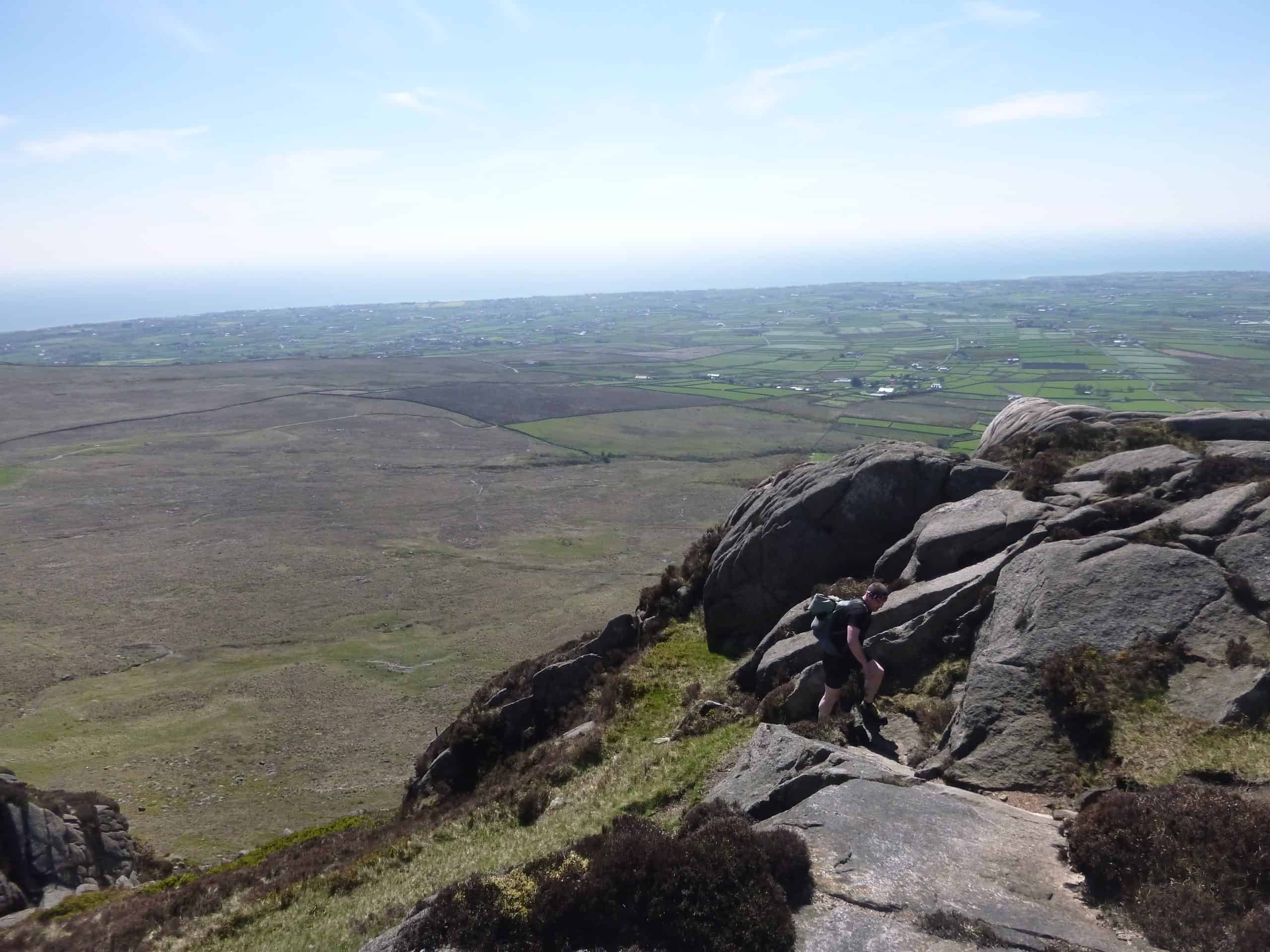 Rough stone wall on a mountain trail at dusk with dark sky and shadowed landscape, outdoor hiking scenery, rugged trail, natural landscape, adventure hiking, scenic mountain path, wilderness exploration, remote outdoor environment.