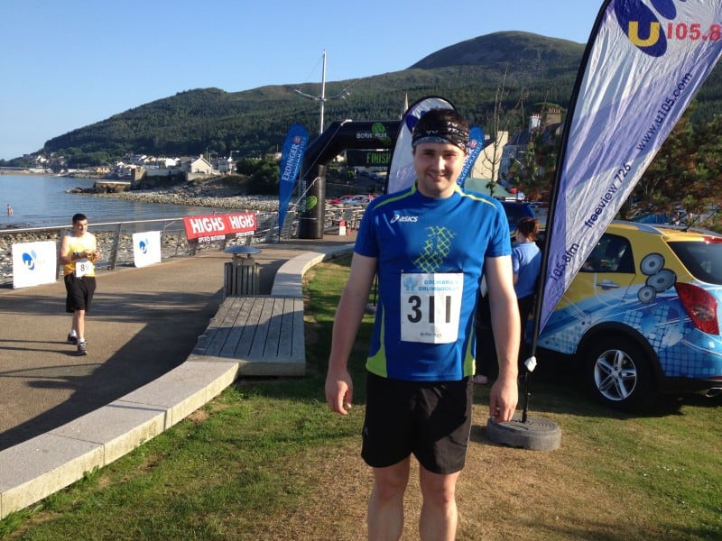 Sea to Sky 10k Runner at finish line with scenic coastal background during a trail race on a sunny day.