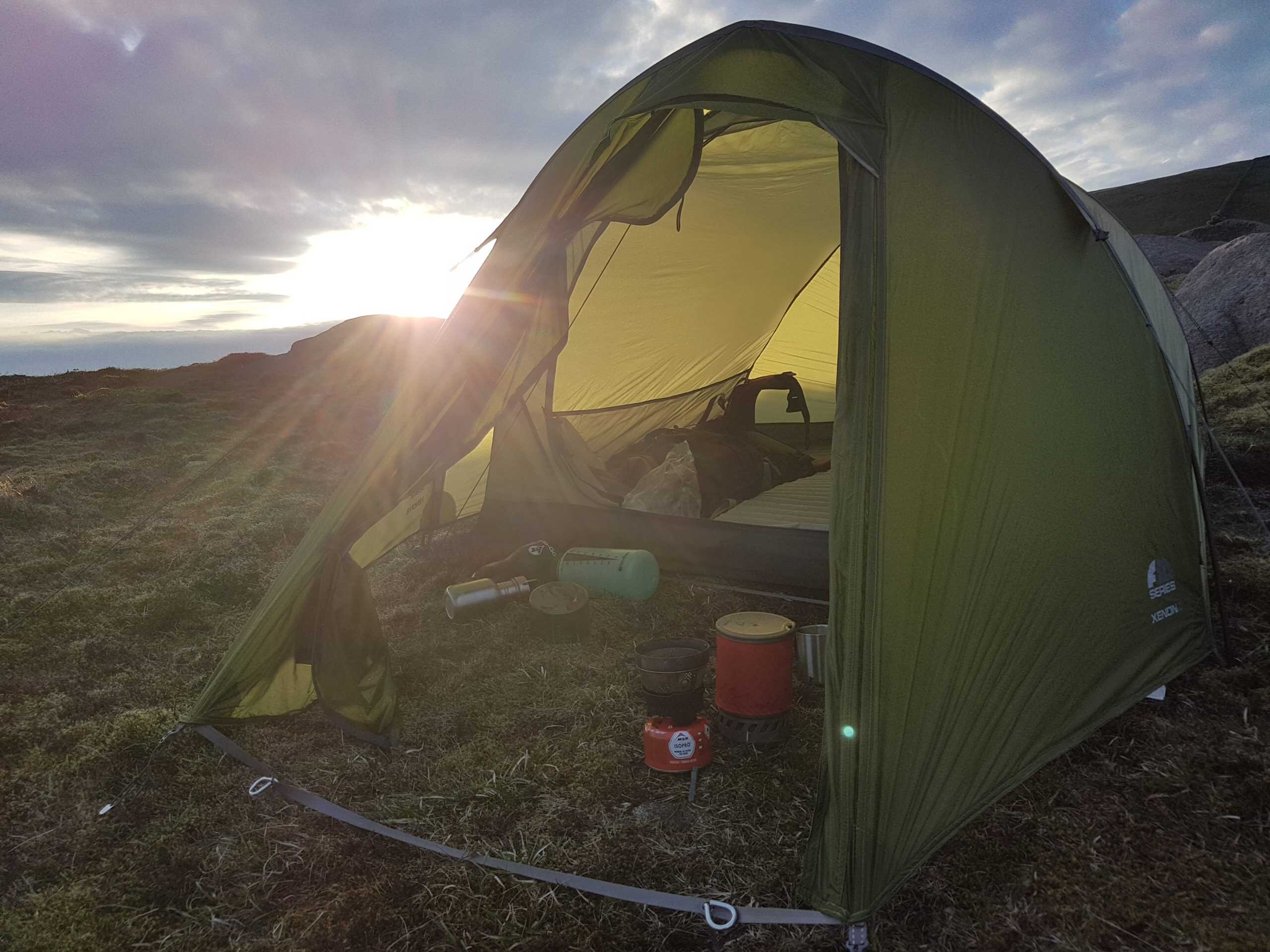 Vango F10 Xenon UL 2 Review Bright yellow camping tent set up outdoors at sunset, surrounded by nature, perfect for hiking and adventure trips. Ideal for outdoor enthusiasts seeking camping gear inspiration.