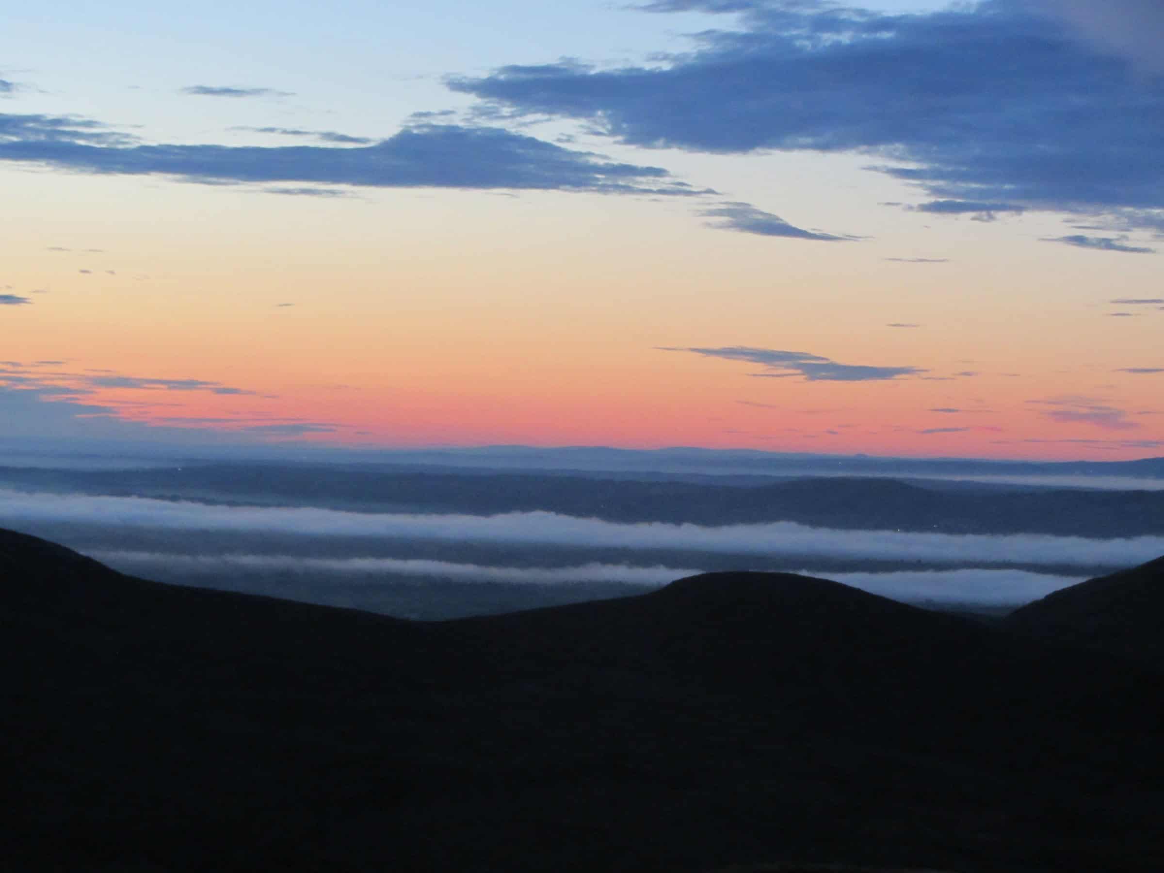Sunset Ascent of Pigeon Rock Dawn over rolling hills with colorful sky and cloud formations, capturing serene landscape for hiking and outdoor adventure content.