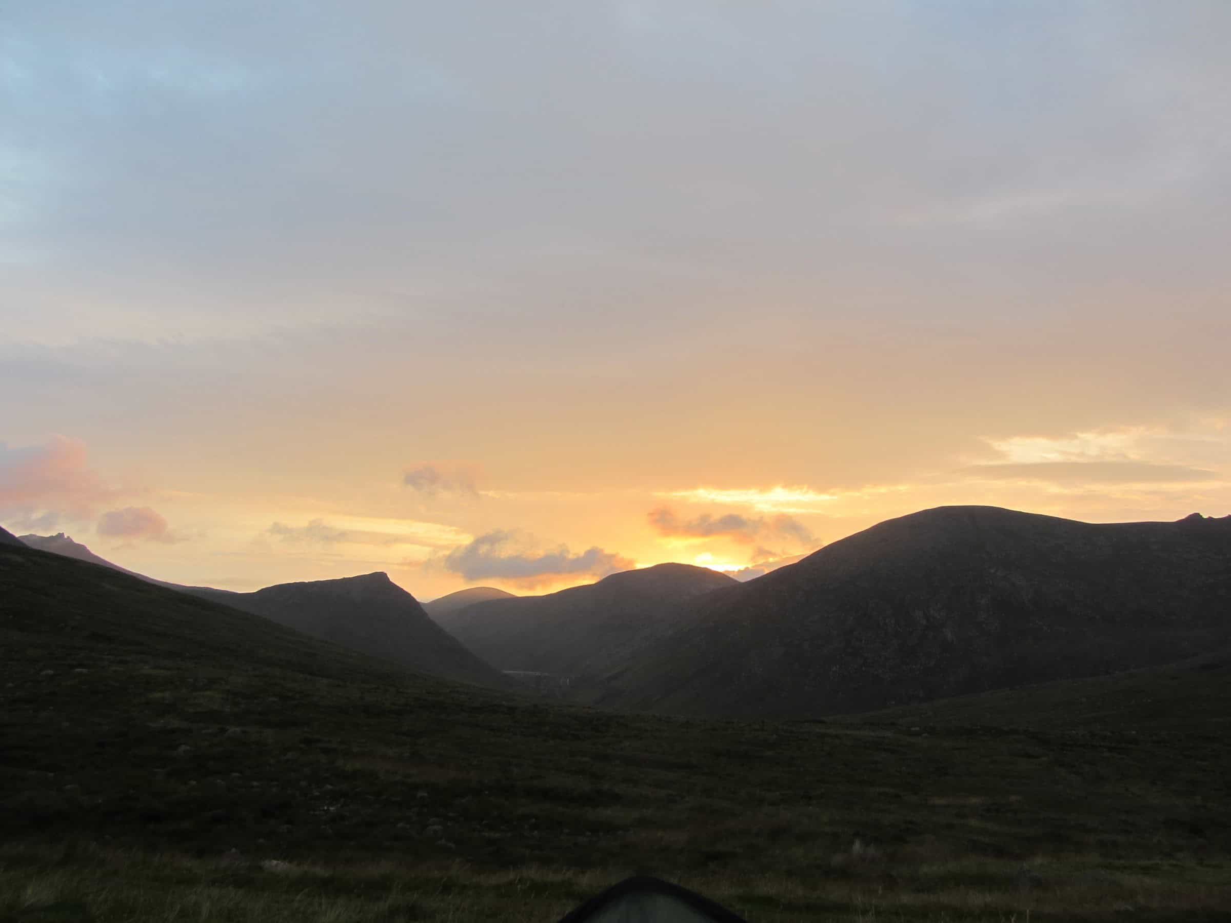 From sunshine to storm Majestic mountain landscape at sunset with rolling hills and a colorful sky, perfect for hiking and outdoor adventure enthusiasts.