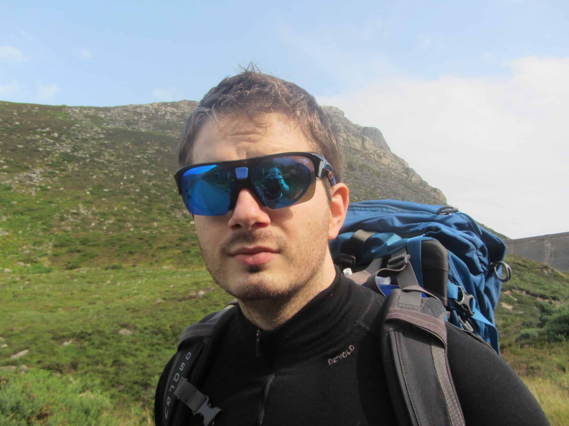 SportViz XTS Core Hiking Prescription Sunglasses Optical sports sunglasses worn by a hiker with a backpack on a mountainous trail, outdoor adventure, and hiking tourism.