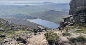 Three Summer Days in the Mournes with a Bivi Breathtaking mountain trail overlook showing a lake surrounded by rugged terrain and stone formations, perfect for hiking and outdoor exploring in nature.