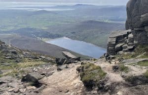 Three Summer Days in the Mournes with a Bivi Breathtaking mountain trail overlook showing a lake surrounded by rugged terrain and stone formations, perfect for hiking and outdoor exploring in nature.