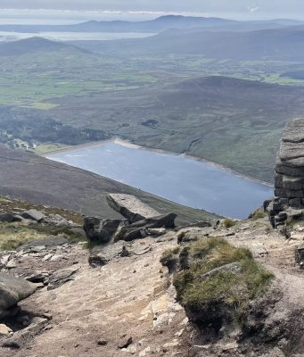 Three Summer Days in the Mournes with a Bivi Breathtaking mountain trail overlook showing a lake surrounded by rugged terrain and stone formations, perfect for hiking and outdoor exploring in nature.