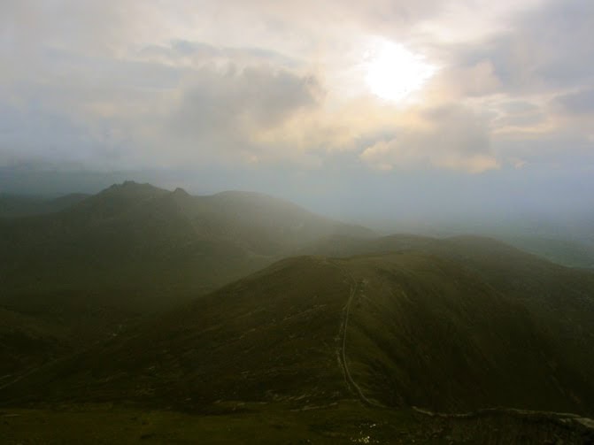 Breathtaking lakeside mountain landscape with rolling green hills and rugged terrain during daytime.