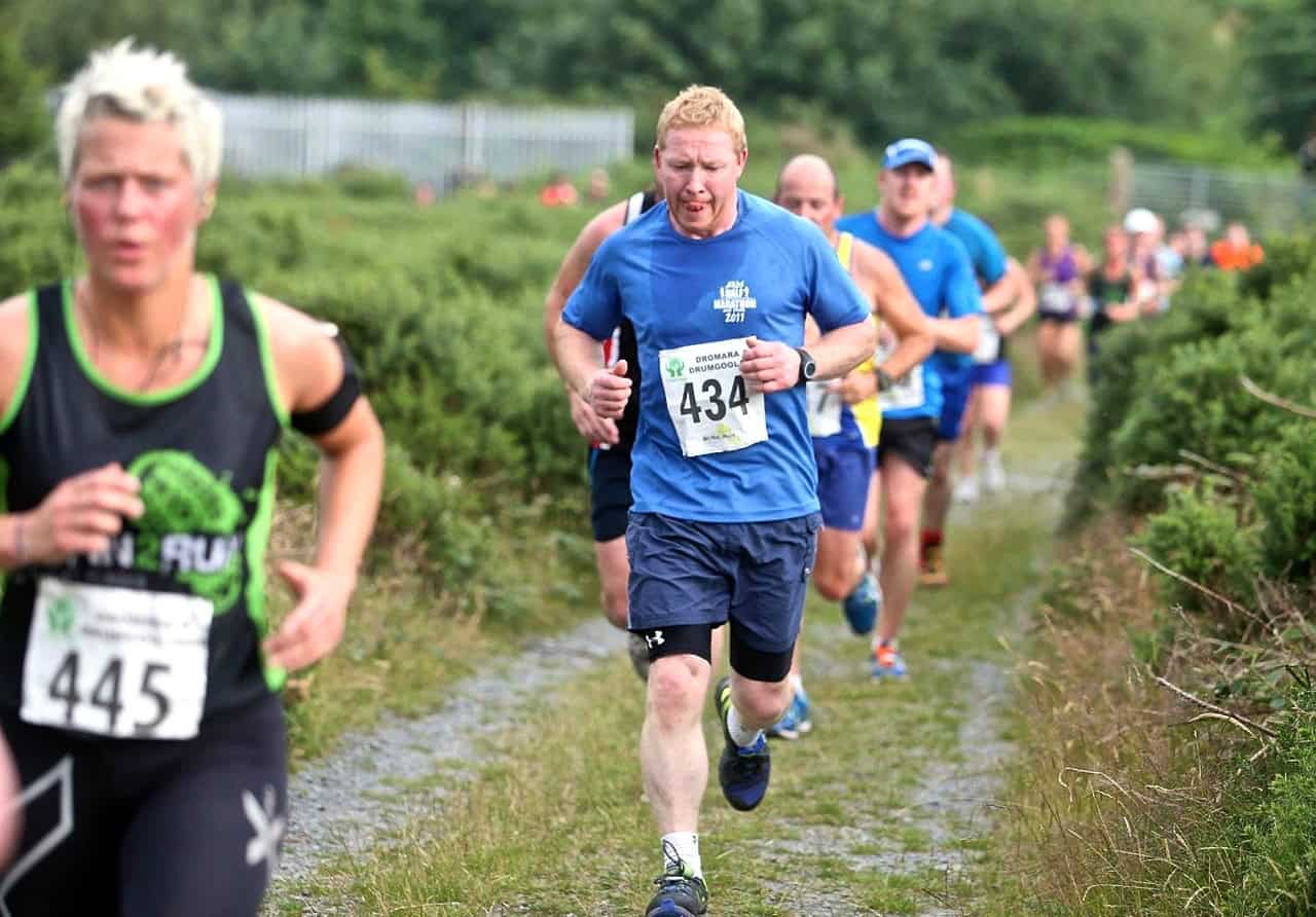 Sea to Summit 10k Runners participating in a trail marathon on a scenic woodland path, showcasing community outdoor fitness and endurance sports, with vibrant sportswear and numbered bibs.